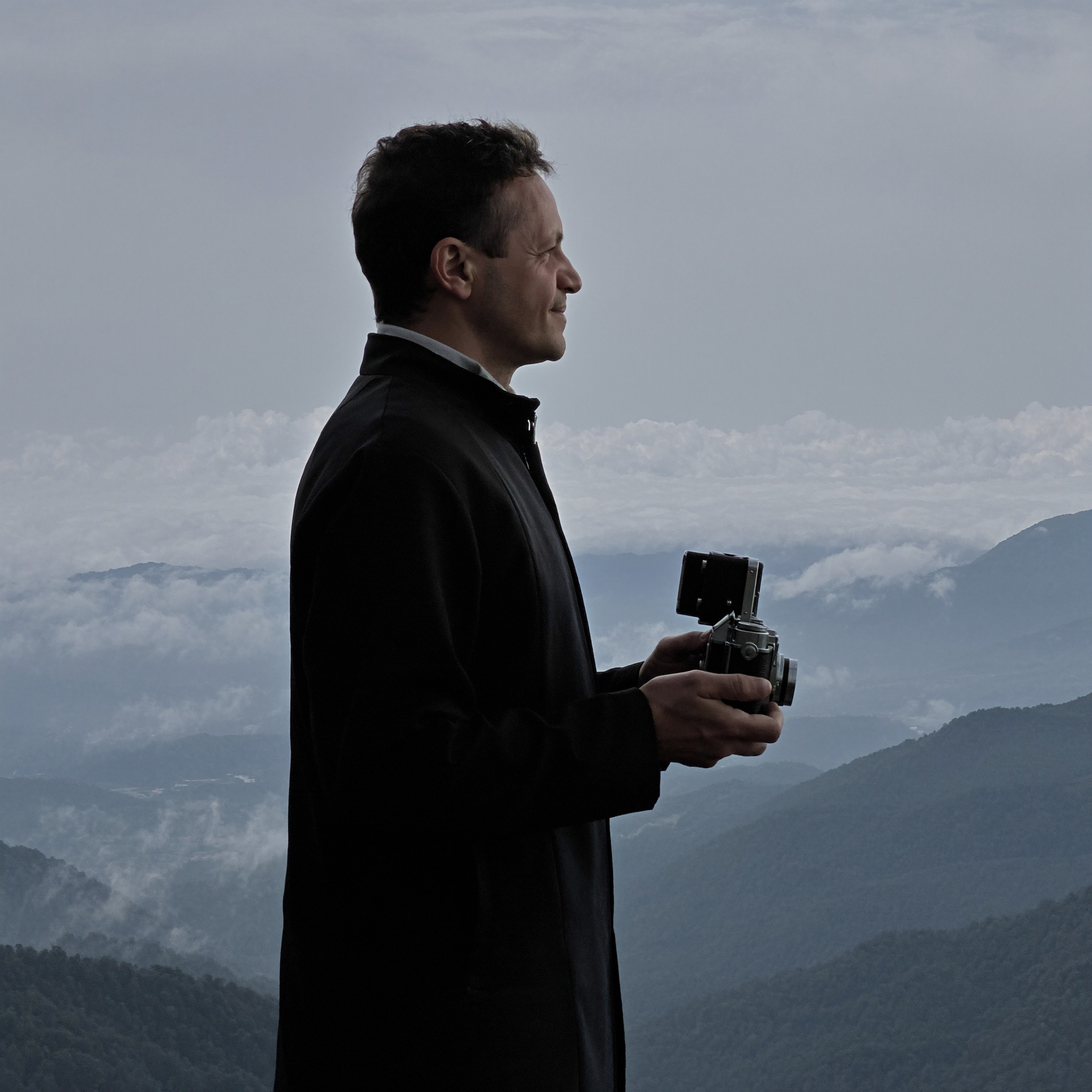 Roberto Pereira Eisenlohr with vintage camera on a misty mountaintop