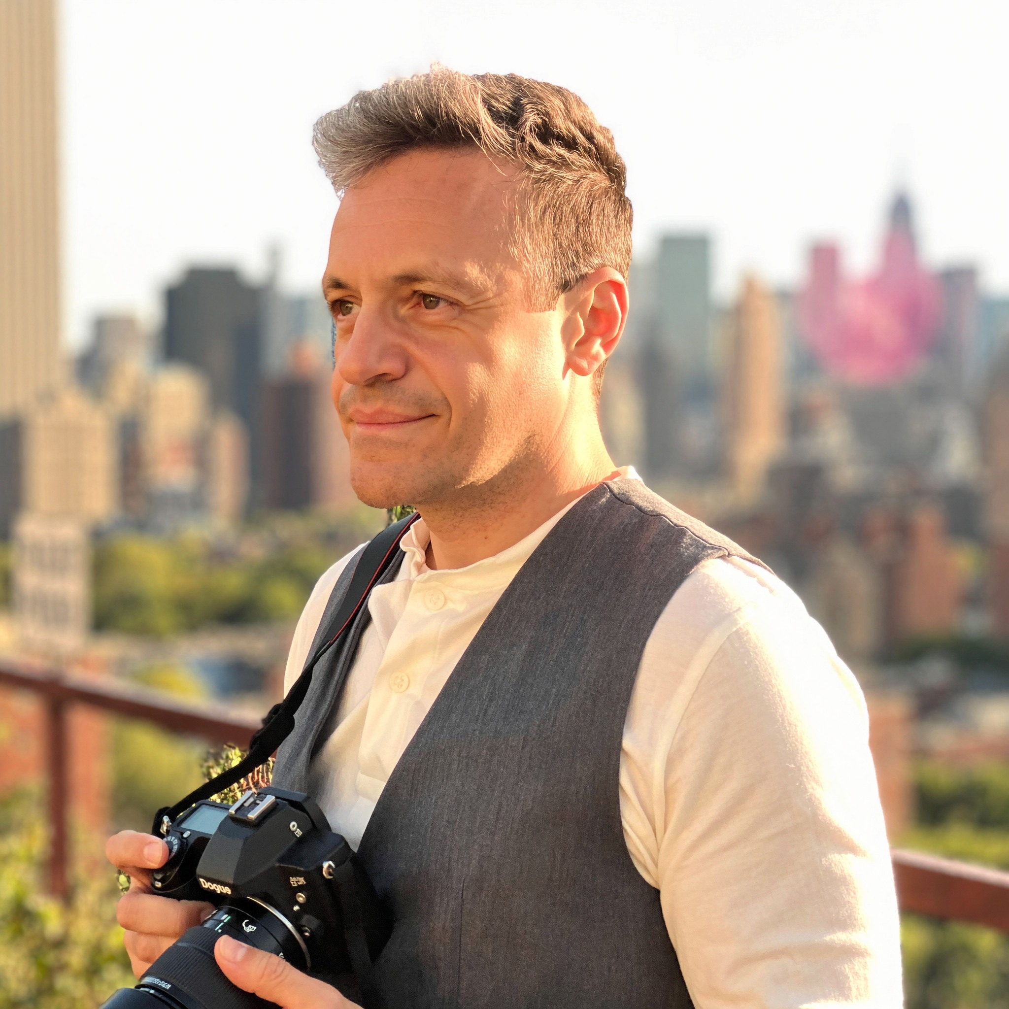 Roberto Pereira Eisenlohr with camera on a Manhattan rooftop at golden hour